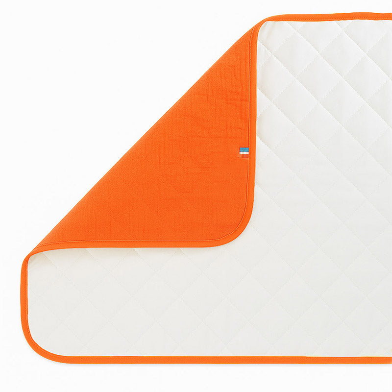 Pusleunderlag i økologisk bomuld – sammenklappeligt og vandafvisende med blød polstring, perfekt til skift hjemme og på farten.